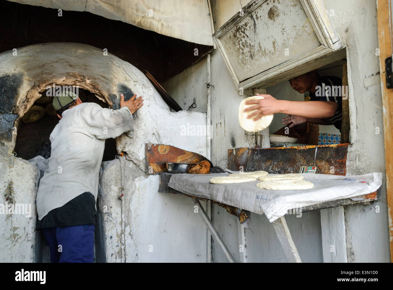 La gente haciendo pan en un horno tradicional, Uzbekistán, en el Asia Central. Foto de stock