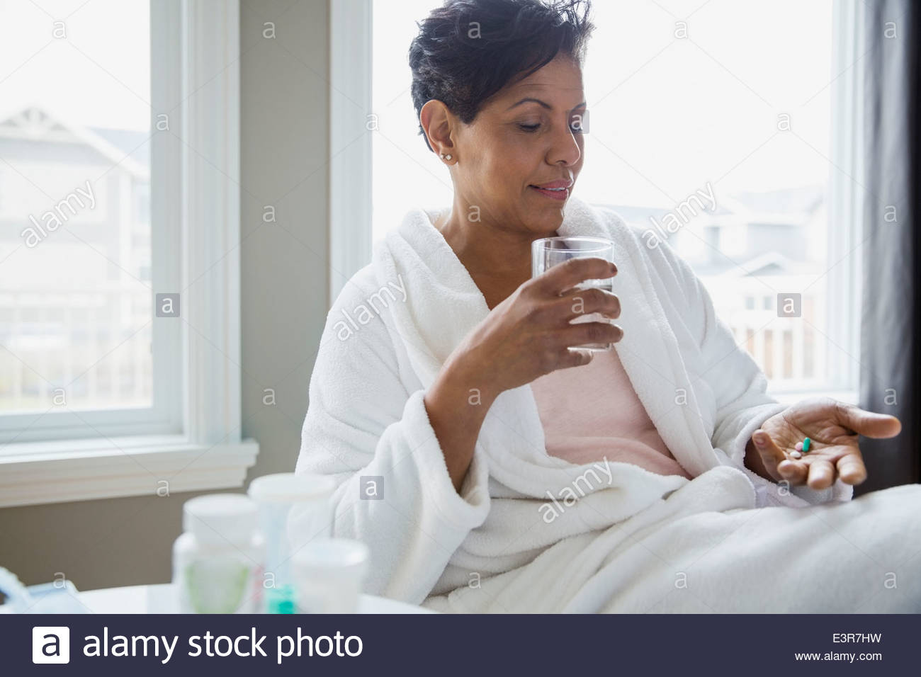 Mujer en albornoz tomando vitaminas Foto de stock