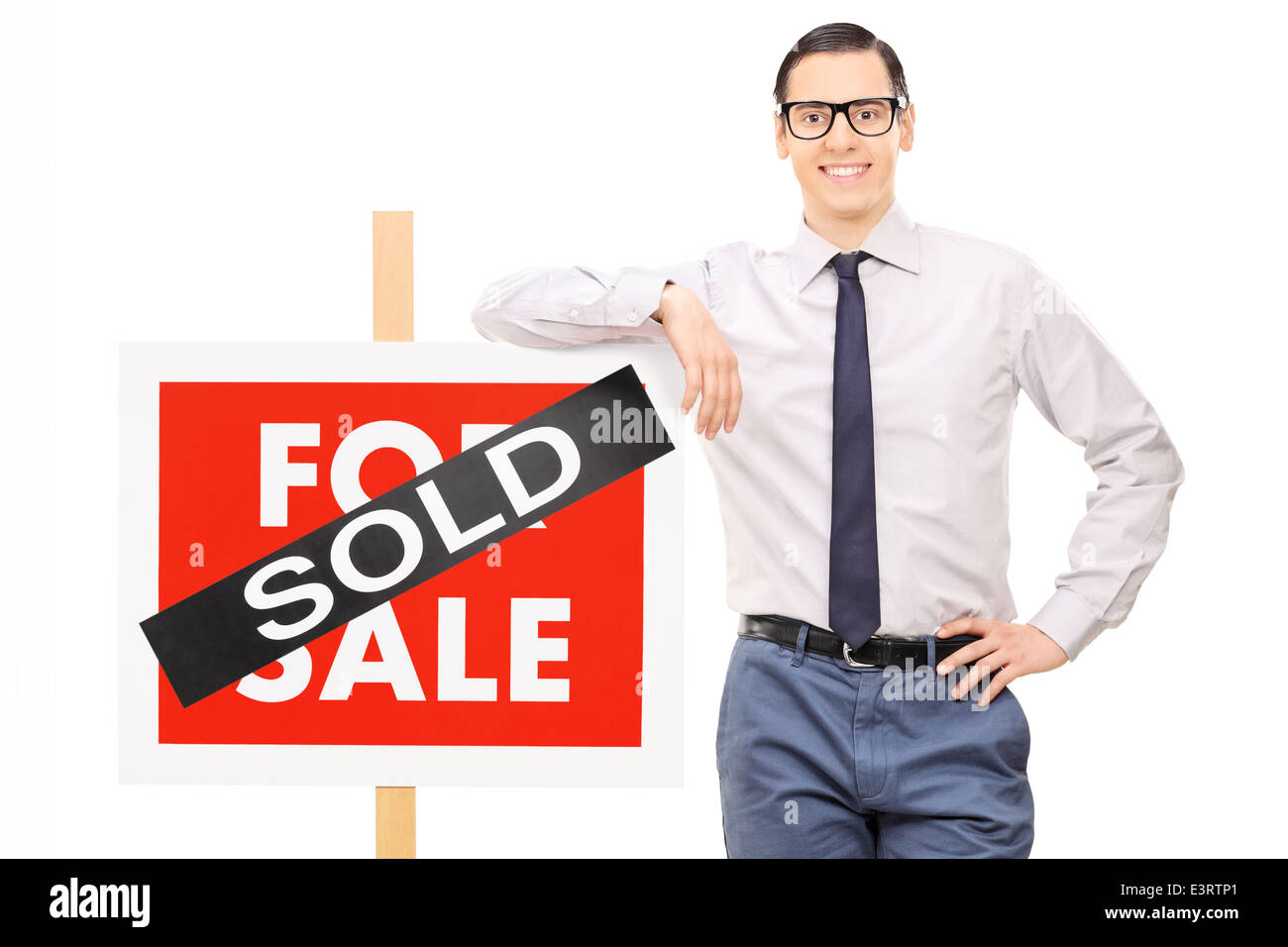 Agente inmobiliario macho apoyándose en un signo vendidos Foto de stock