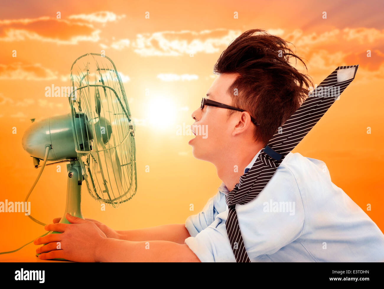La ola de calor que viene, hombre de negocios sosteniendo un ventilador eléctrico Foto de stock
