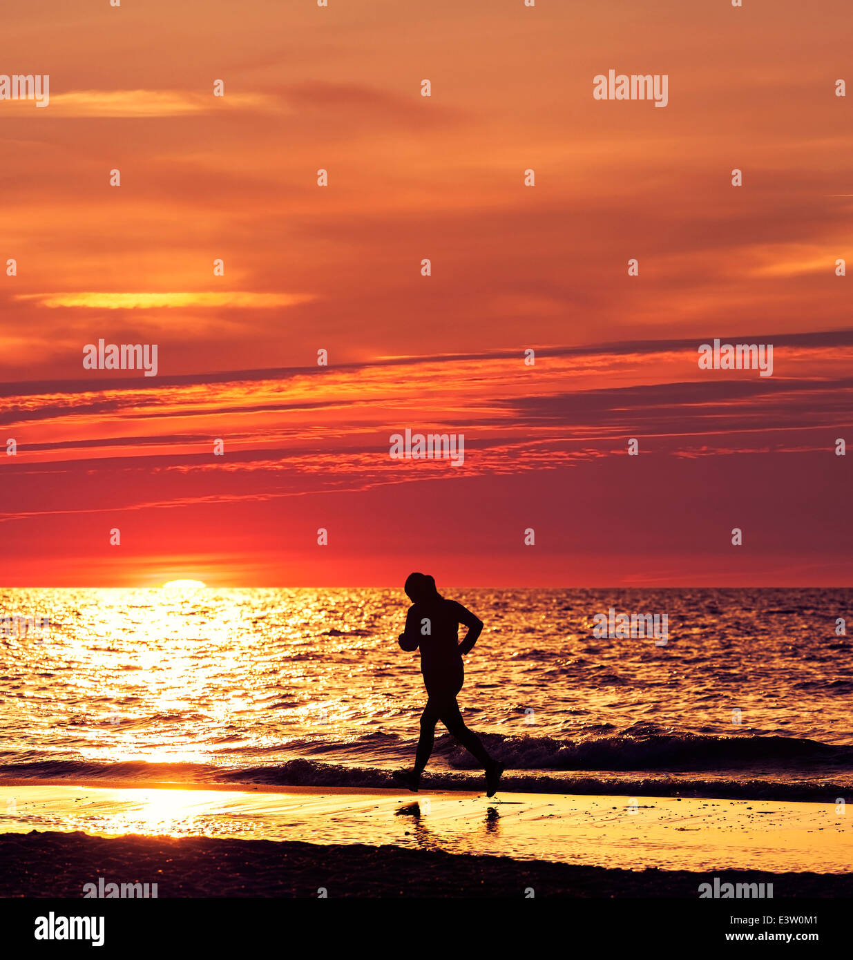 Mujer girando al hermoso atardecer en la playa. Foto de stock