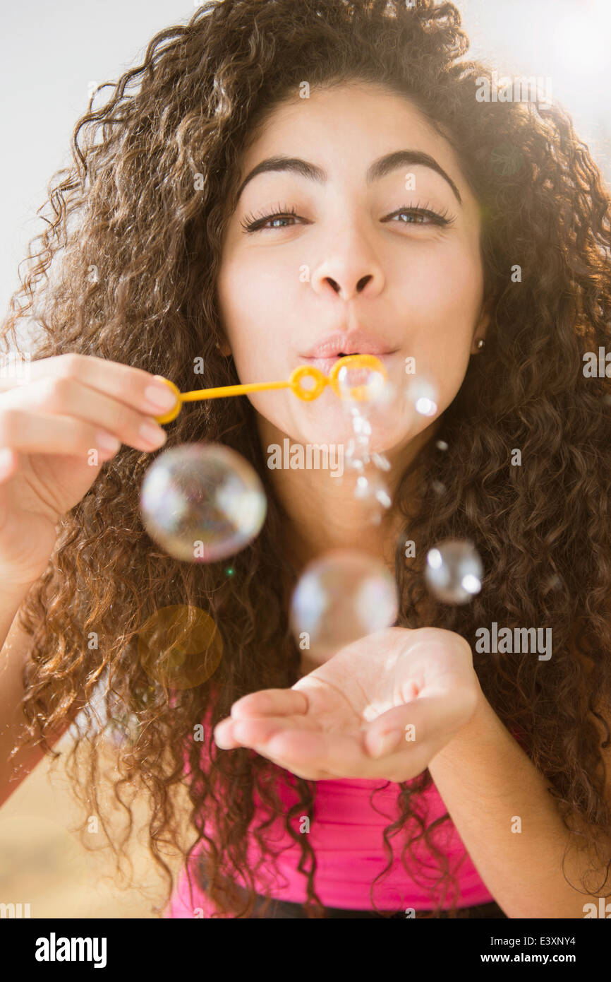 Mujer de raza mixta soplando burbujas Foto de stock