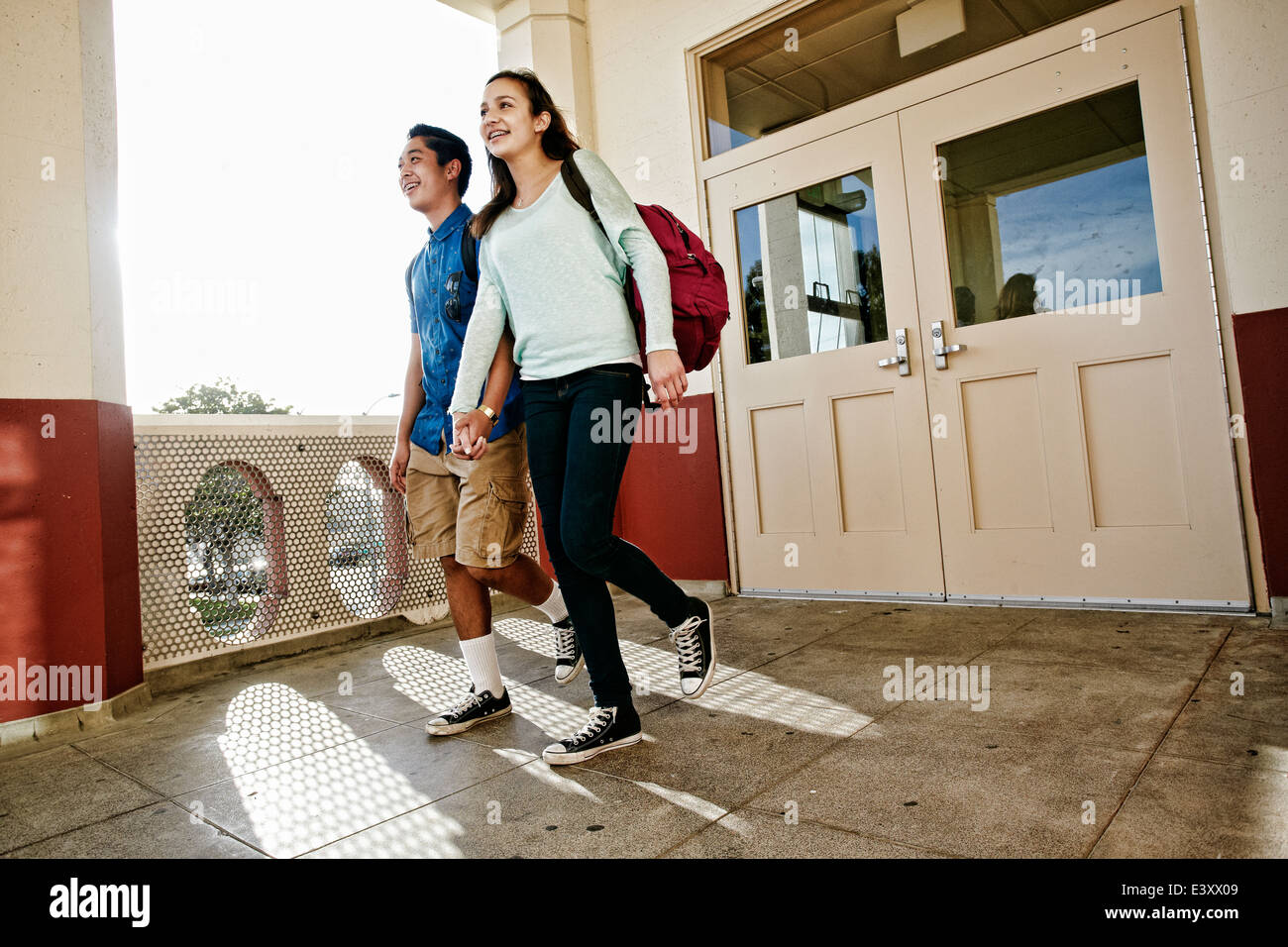 La pareja de adolescentes tomados de la mano en el campus de la escuela Foto de stock