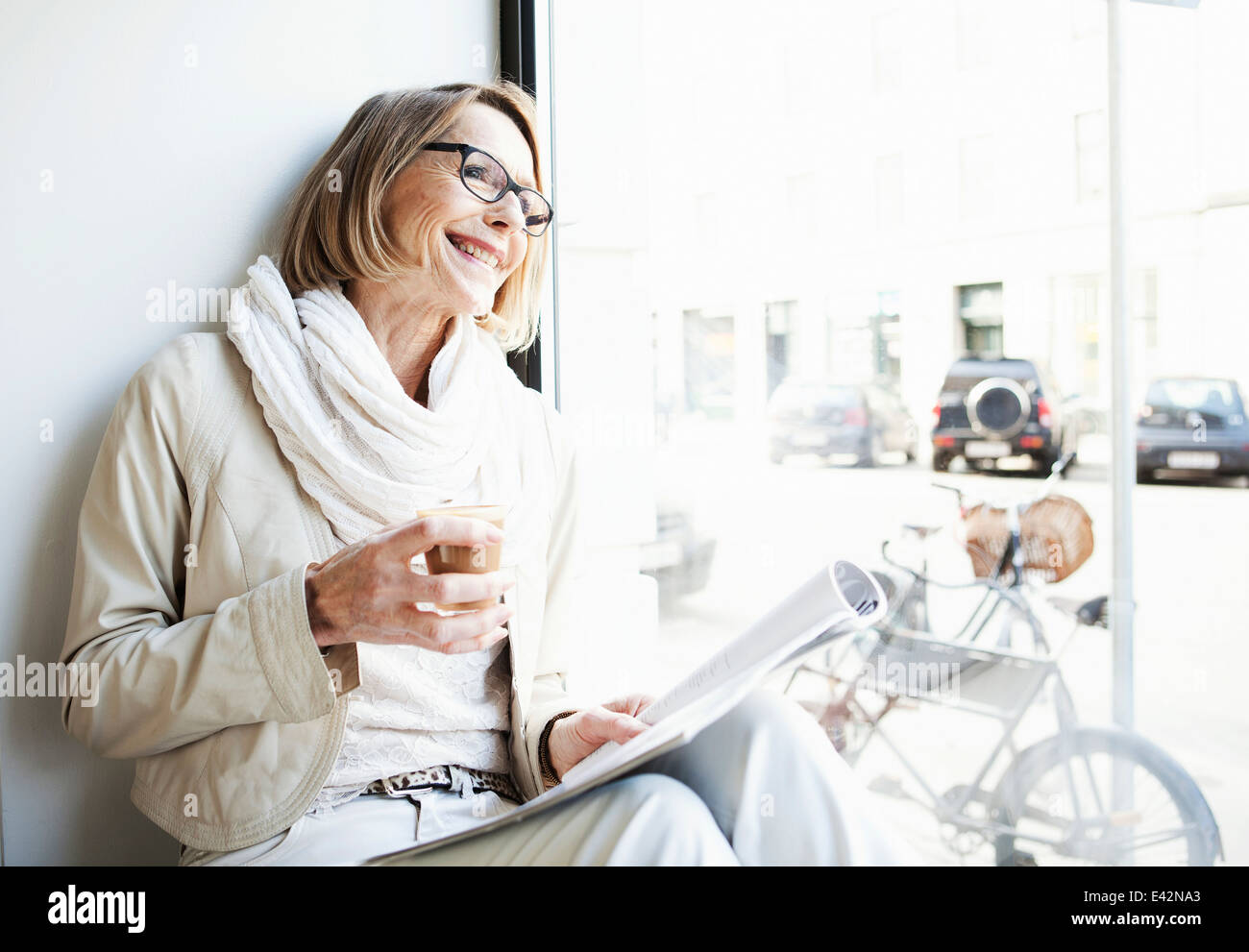 Mujer mayor tomando un café en la cafetería del asiento de ventana Foto de stock