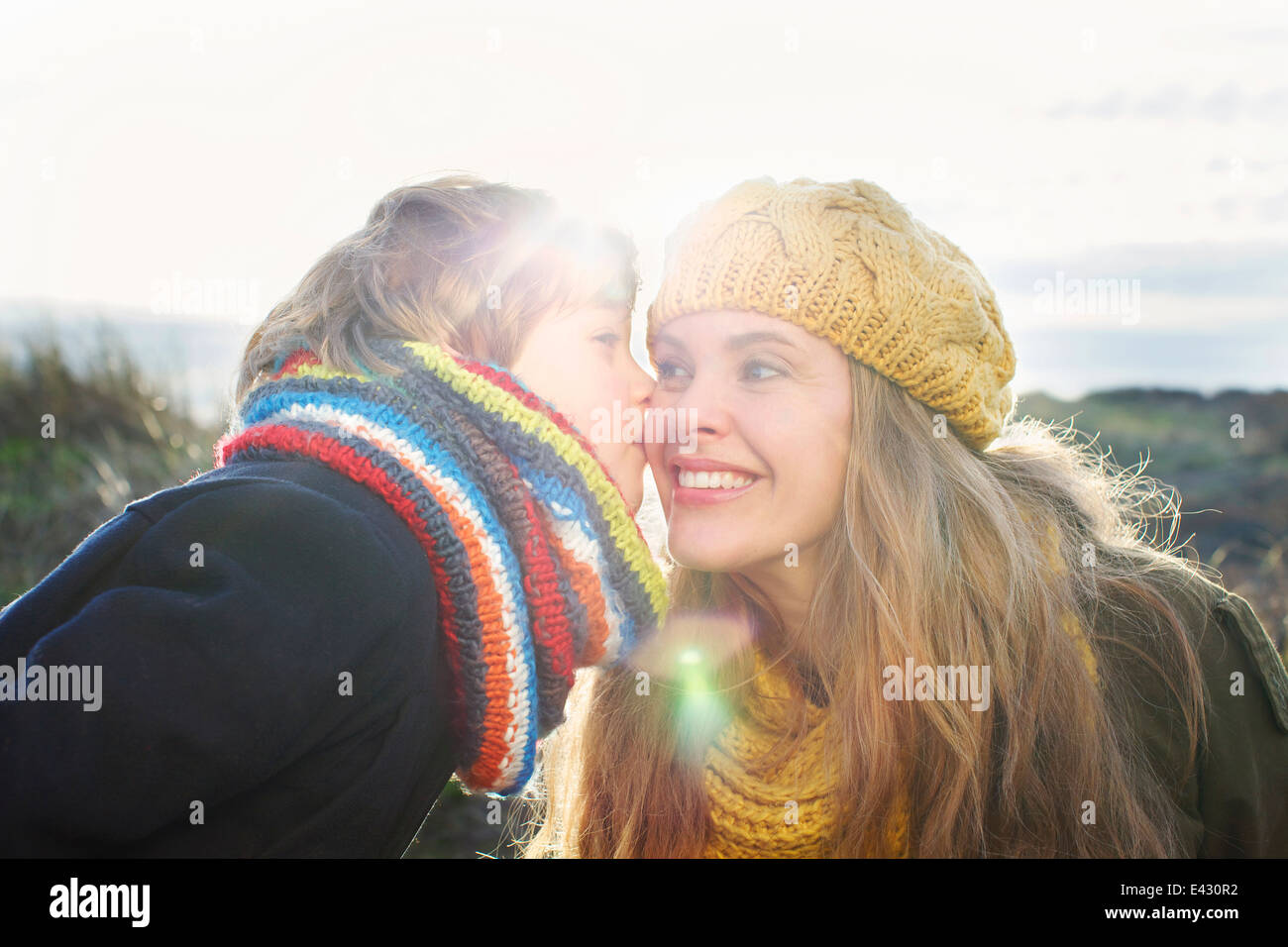 Mitad mujer adulta con hijo besar su mejilla en la costa Foto de stock