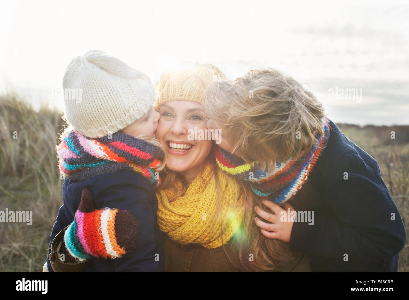 Mitad mujer adulta con hijo e hija besar su mejilla en la costa Foto de stock
