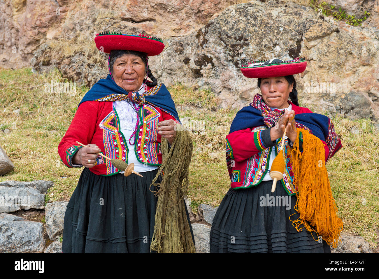 Dos ancianas con sombreros, Indios Quechua, en traje tradicional, hilando lana con husillos de madera, Cinchero Foto de stock