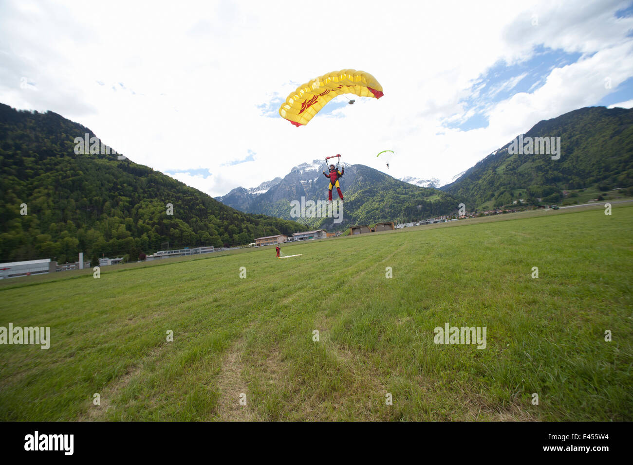 Equipo de tres paracaidistas con paracaídas en el campo de aterrizaje, Interlaken, Berna, Suiza Foto de stock