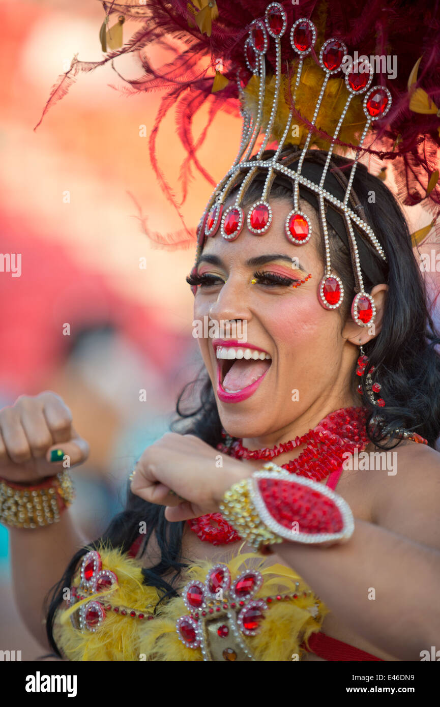 Hermosa mujer brasileña vistiendo coloridos trajes de carnaval y sonriendo  durante el desfile de carnaval en la ciudad.