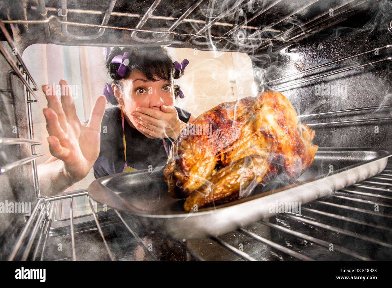 Ama de casa prepara pollo asado en el horno, vista desde el interior de la estufa. La cocción en el horno. Foto de stock
