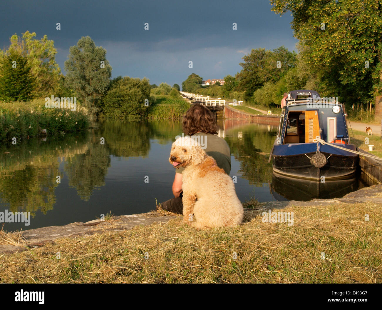 Hombre y el perro se sentó al lado de la canal, Caen Hill cerraduras de Kennet y Avon Canal, Devizes, Wiltshire, UK Foto de stock