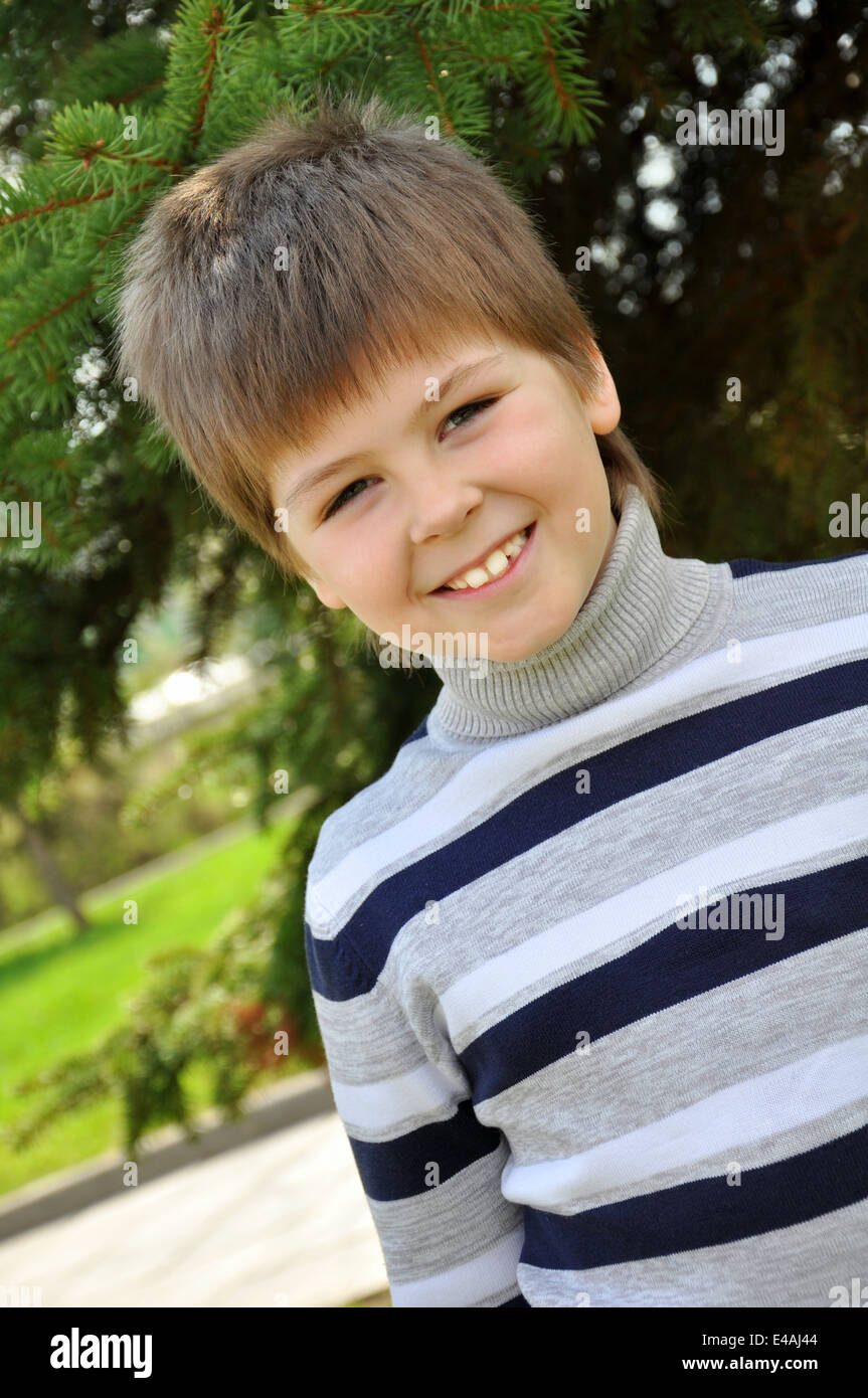 Retrato de un niño de ocho años que vale la pena cuello tortuga suéter cardigan stripe jardines parques rayas verde cabello rubio mira mira da Foto de stock