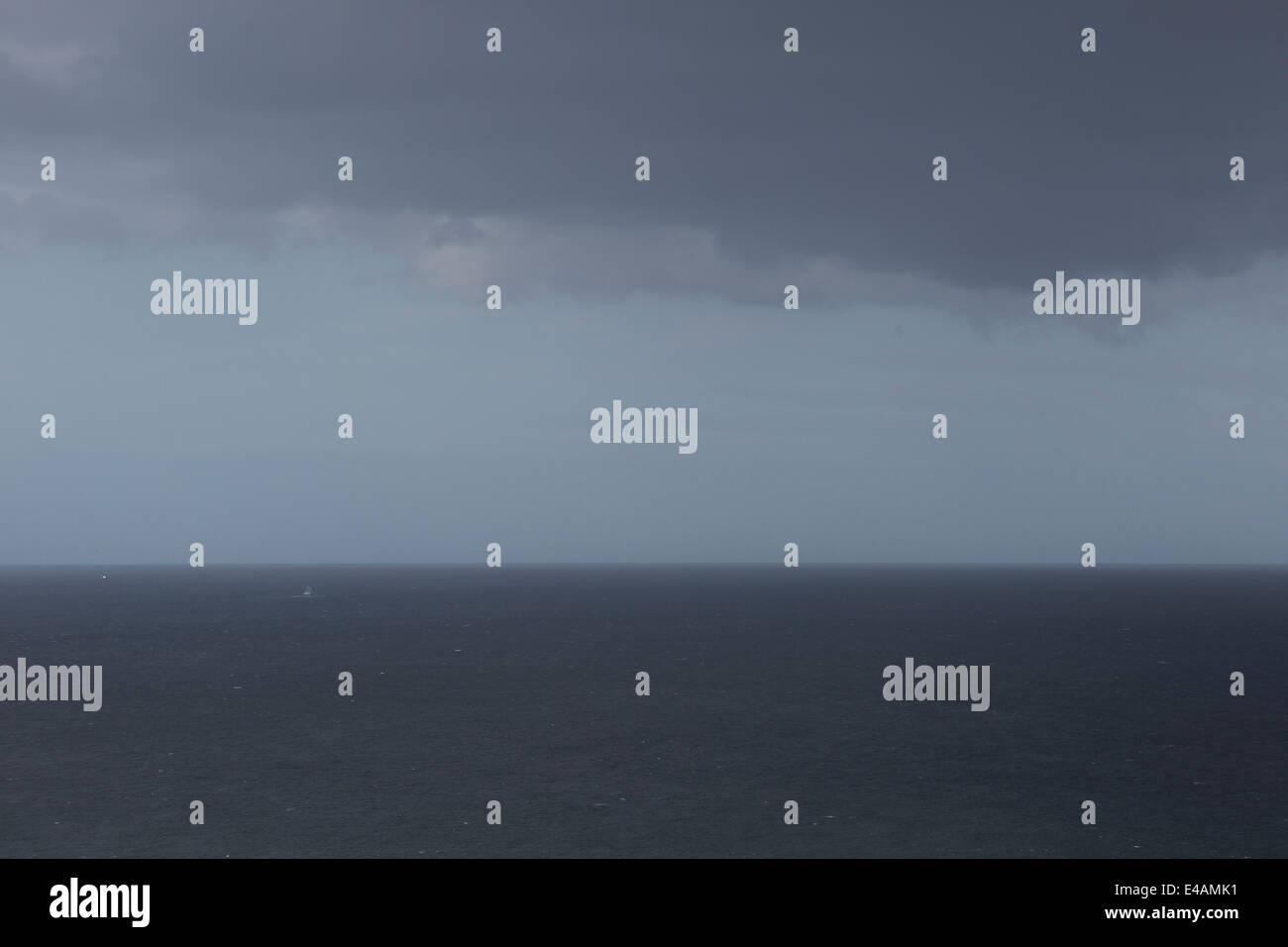 Cielo tormentoso sobre el Atlántico, un pequeño barco pesquero abandona la costa escocesa Foto de stock