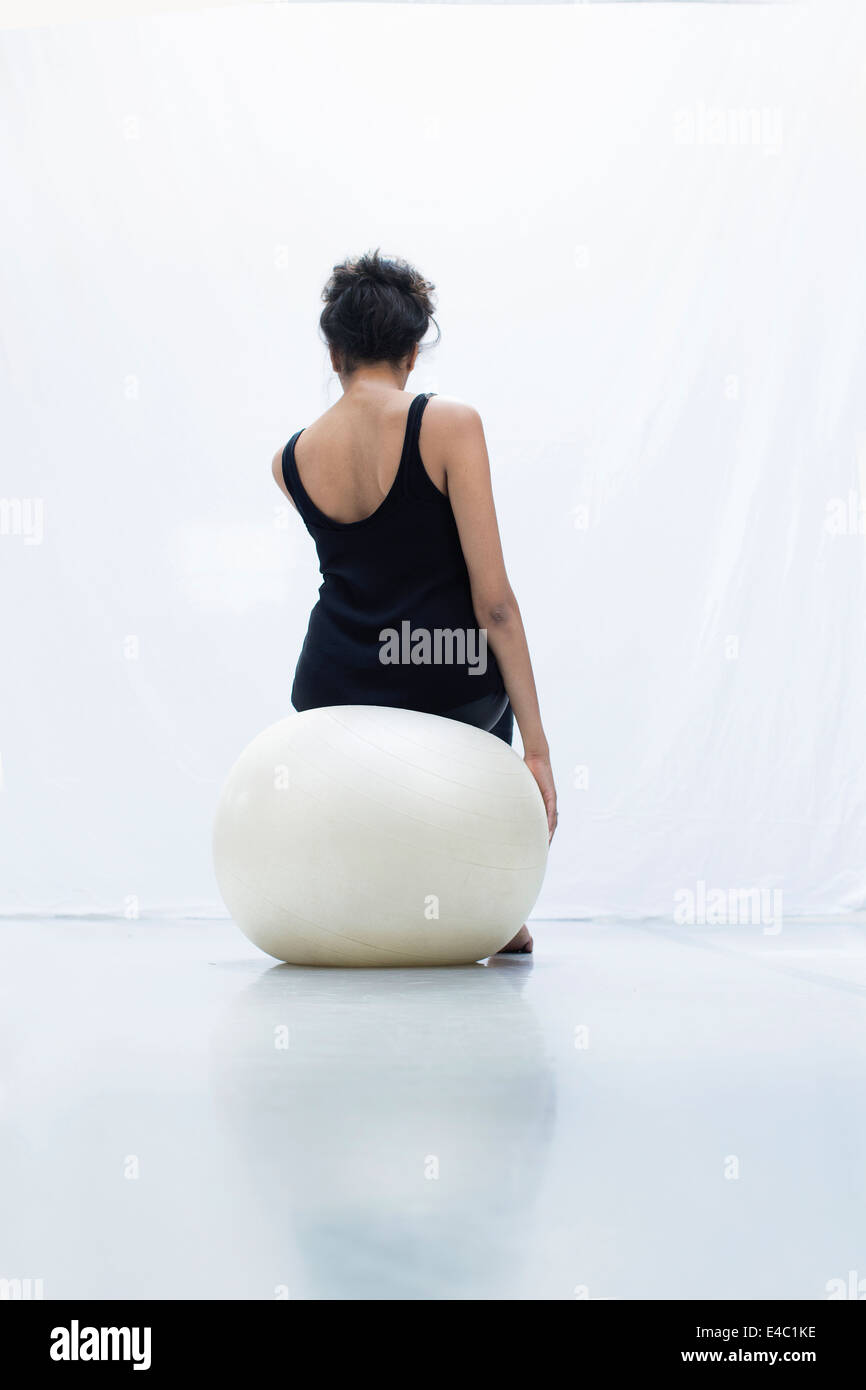 Equilibrio de la mujer sobre la bola del yoga vista trasera foto de estudio Foto de stock
