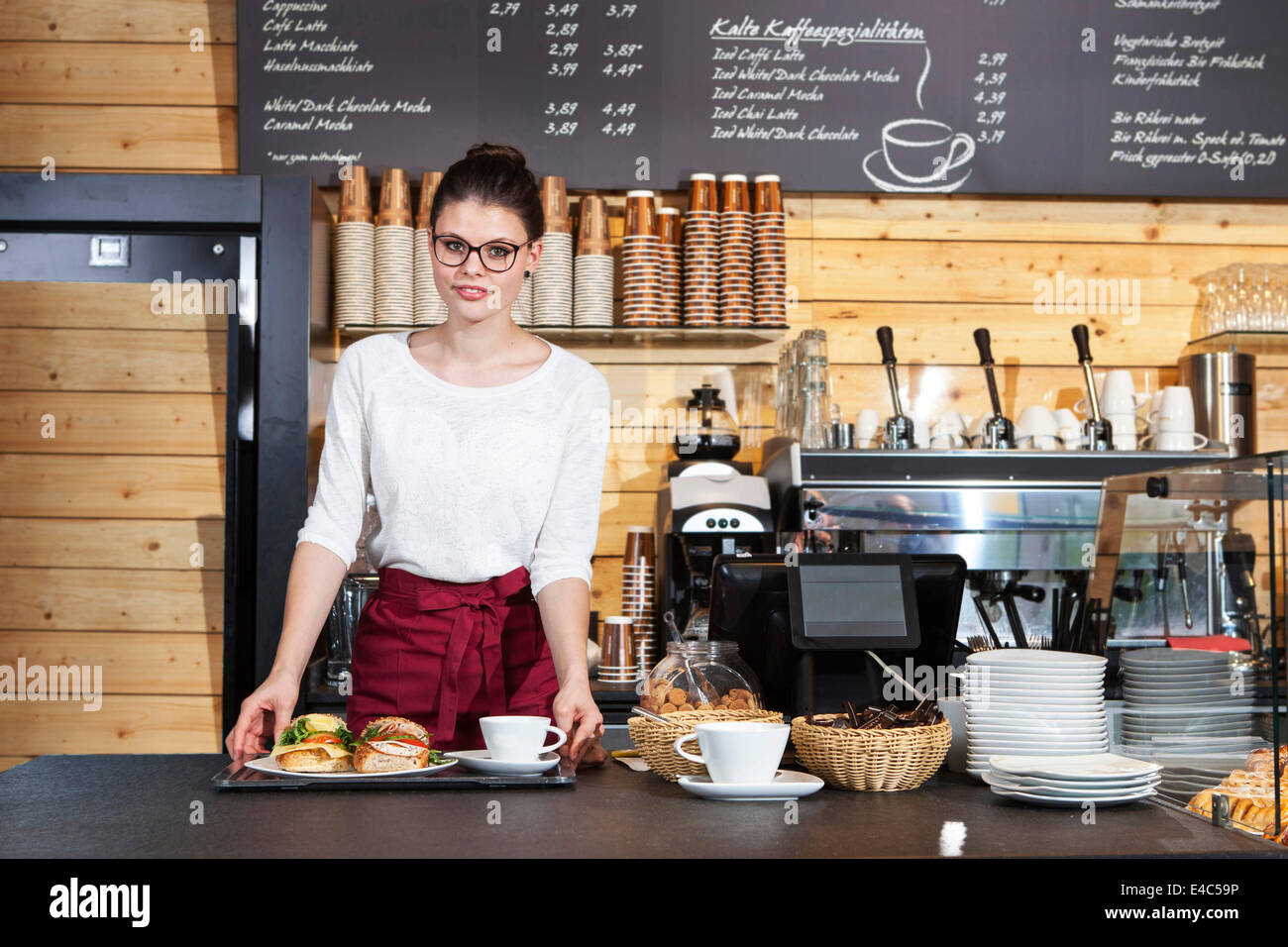 Camarera en la cafetería sirve bocadillos en una bandeja Foto de stock