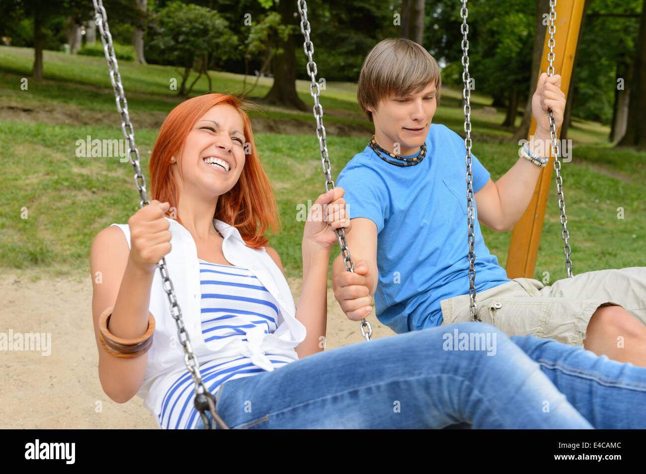 La pareja de adolescentes alegres en el columpio en el parque chica riendo Foto de stock