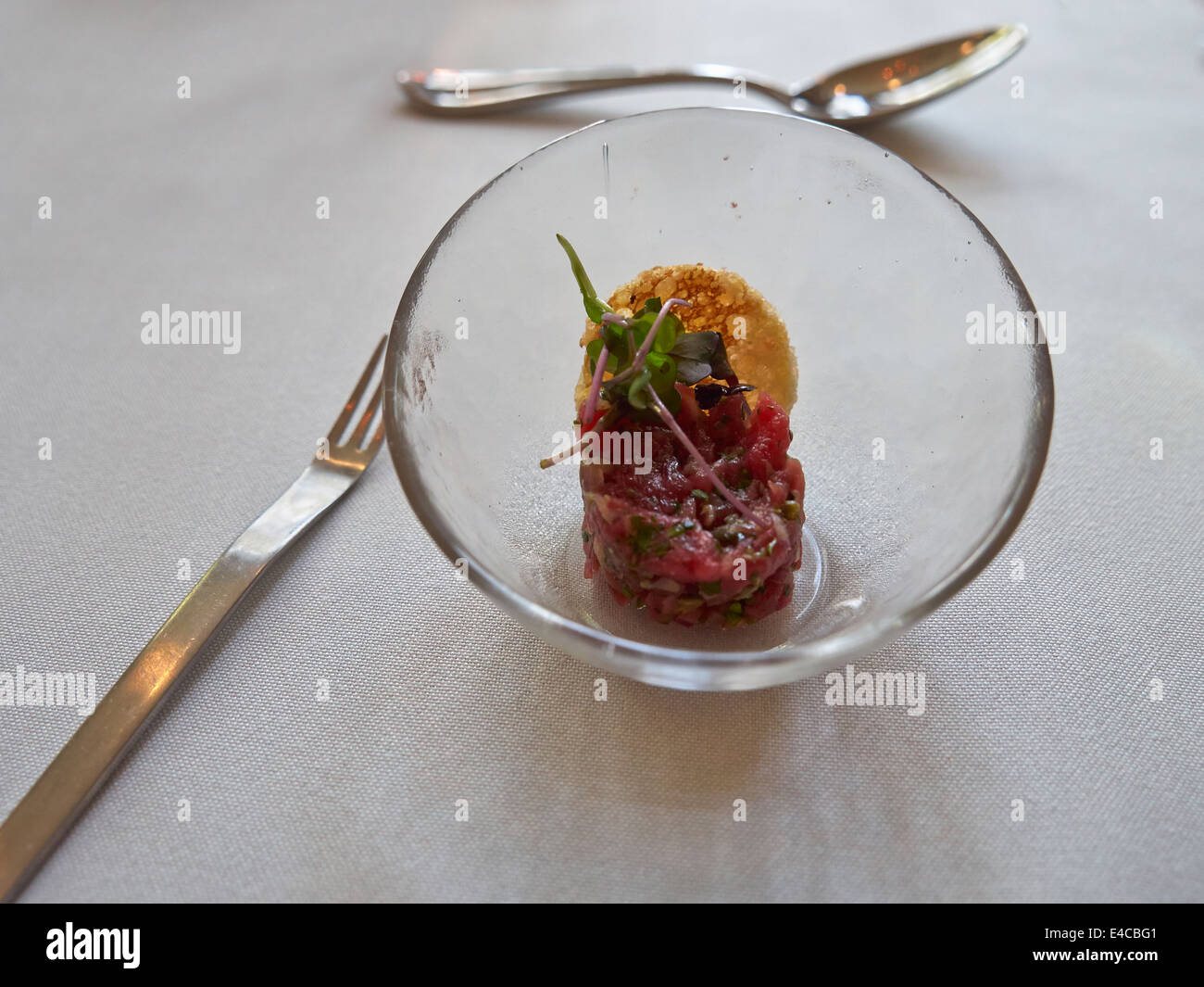 Tartar de carne en un recipiente de cristal con un crouton y los berros Foto de stock