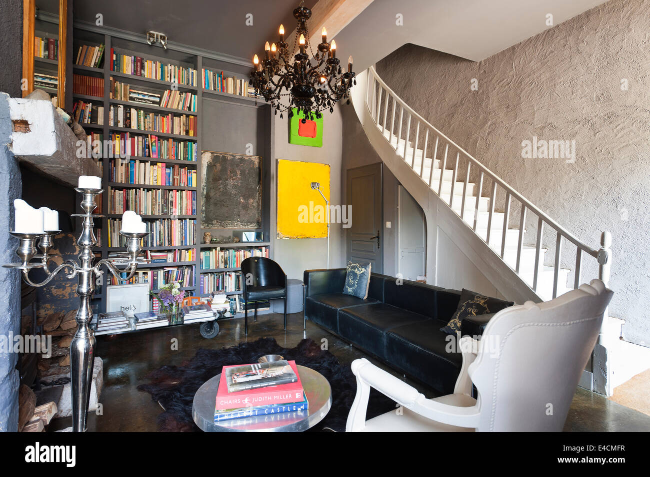 Sala de estar en un palacio restaurado con construido en estantes de libros, Corbusier sofá de cuero negro, blanco y cromo sillón fauteil c Foto de stock