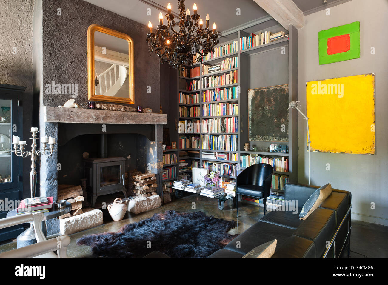 Sala de estar en un palacio restaurado con construido en estantes de libros, Corbusier sofá de cuero negro y cromo candalabra,woodburner fro Foto de stock