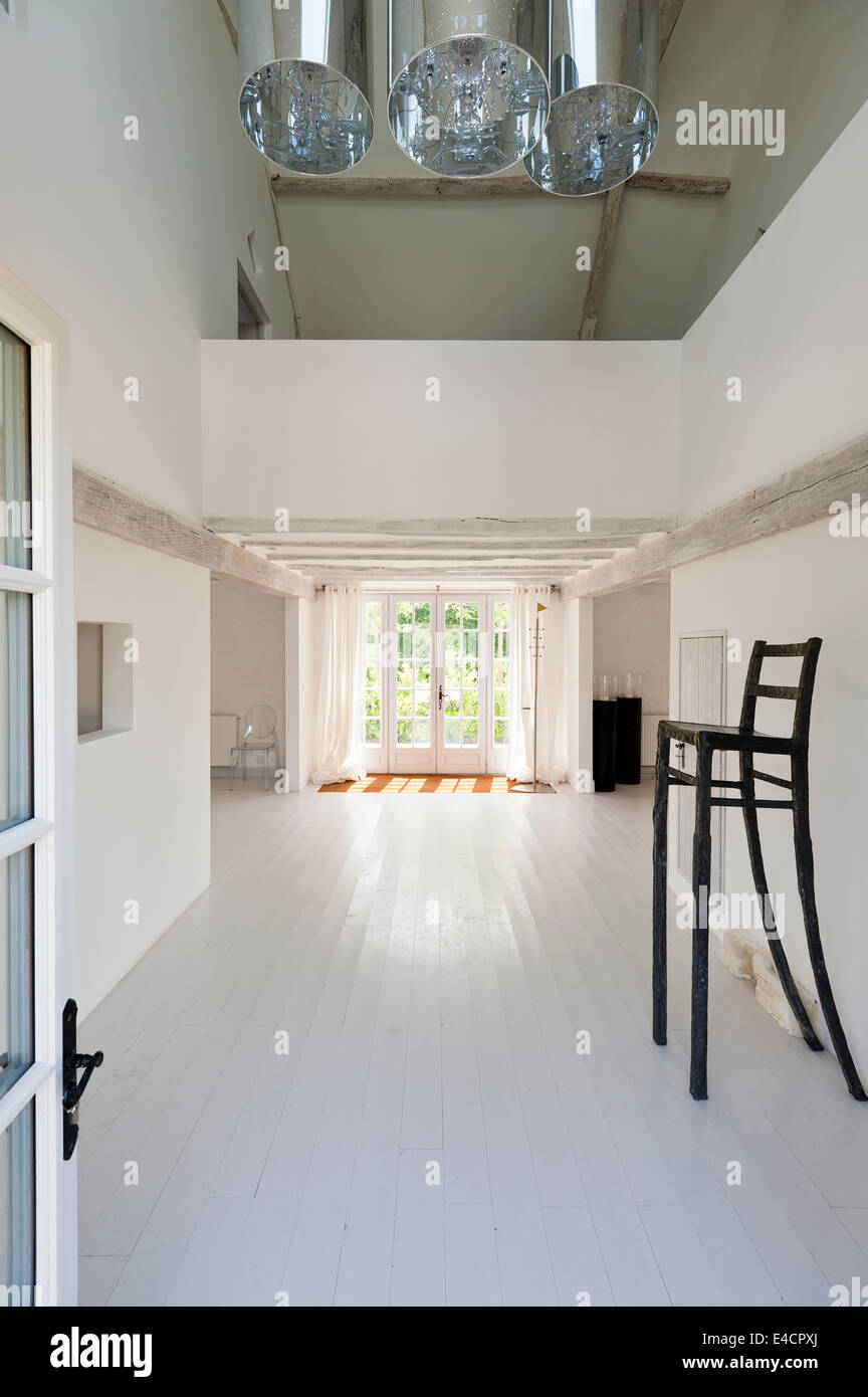 Silla de hierro Alto en plan abierto pasillo blanco minimalista con pisos de madera y techo de vigas Foto de stock