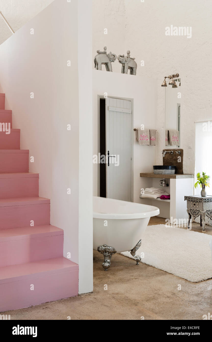 Escalera de color rosa en plan abierto, dormitorio con bañera Foto de stock