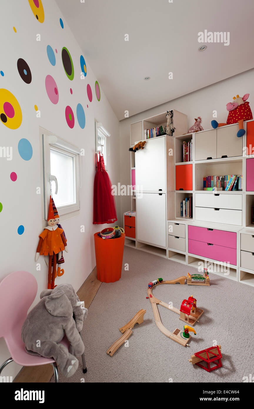 Unidad de almacenamiento modular en niños dormitorio con un surtido de juguetes y un Arne Jacobsen silla Serie 7 Foto de stock