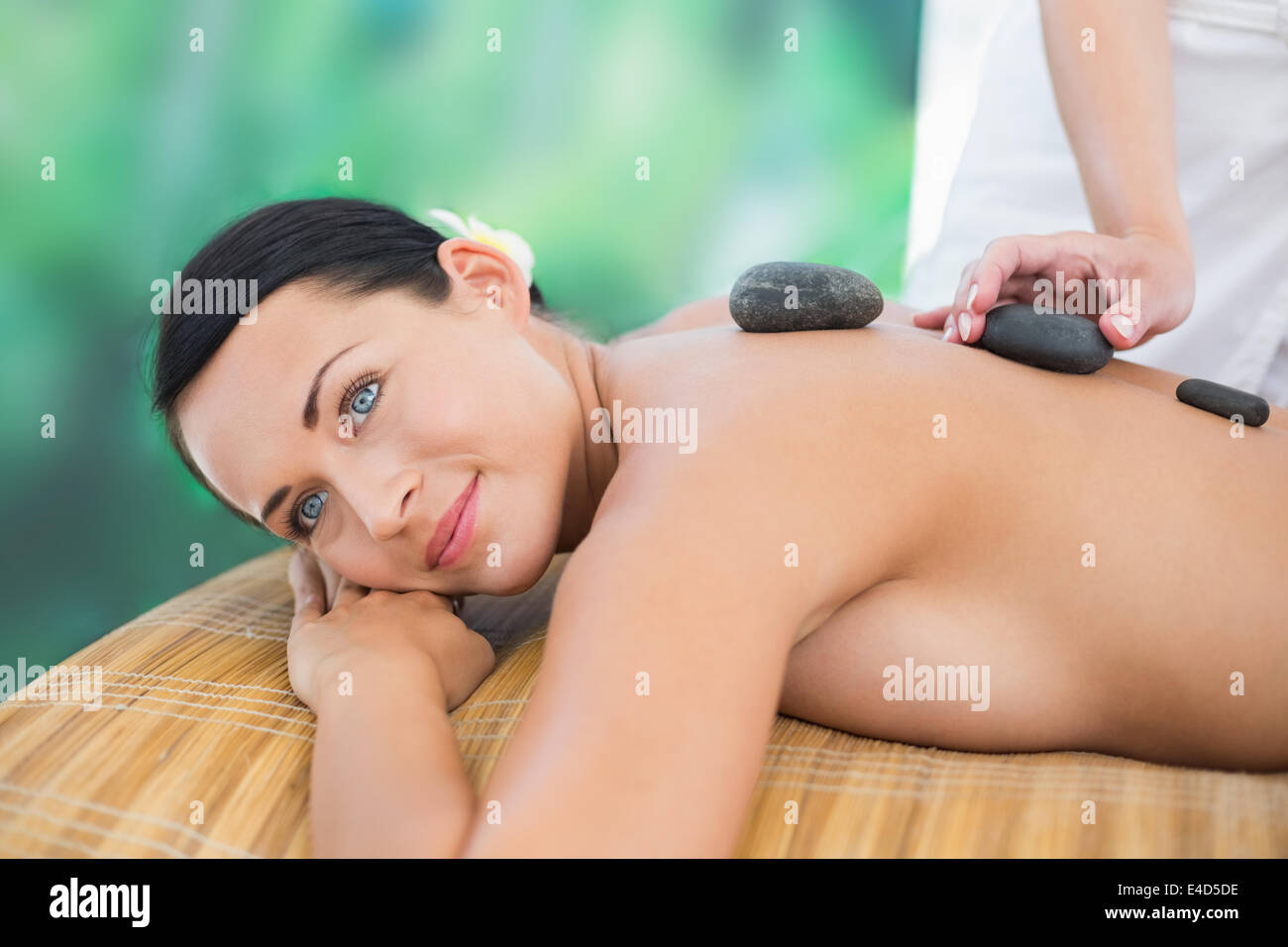 Hermosa morenita disfrutando de un masaje con piedras calientes Foto de stock
