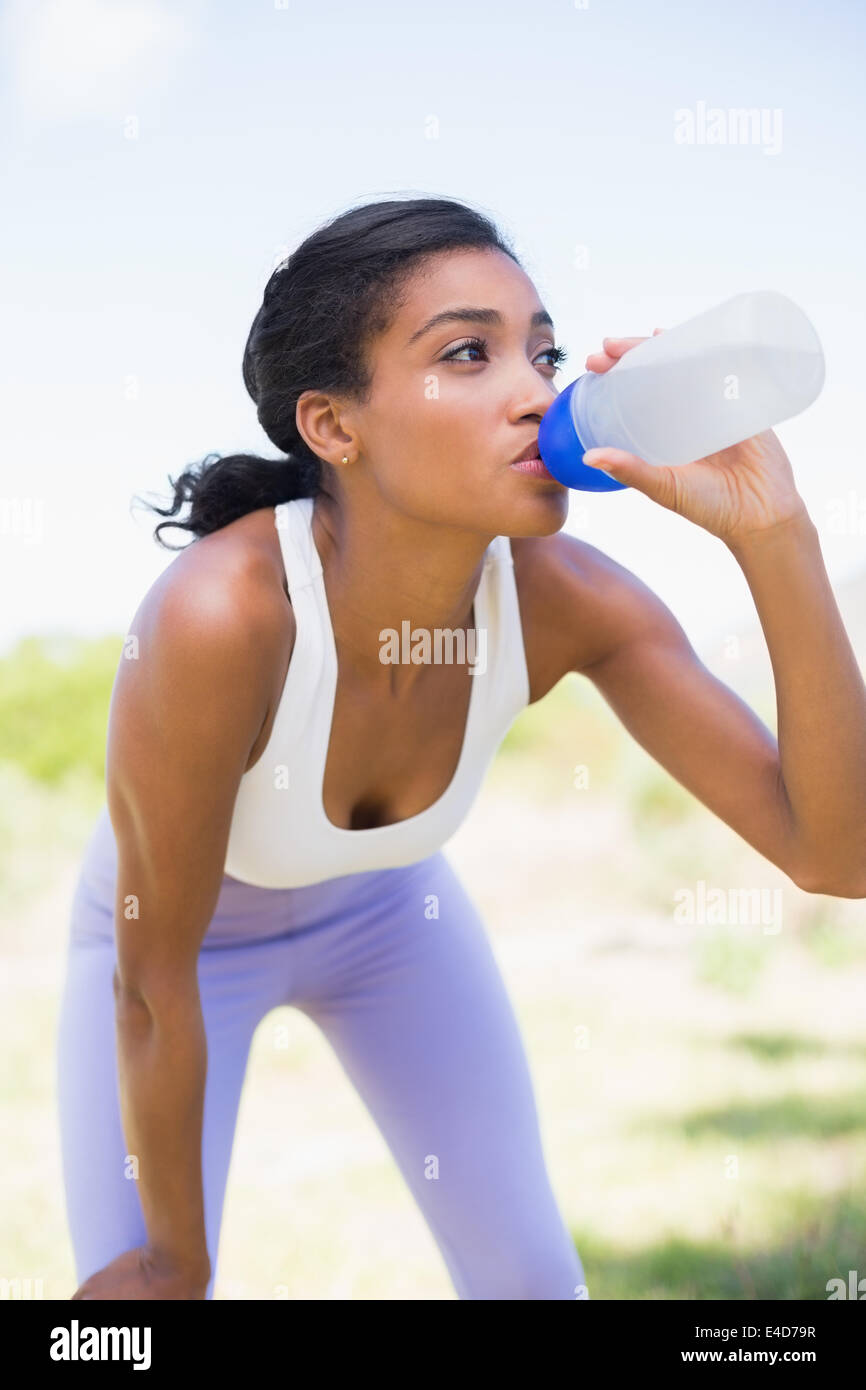 Colocar mujer beber agua de botella de deportes Foto de stock