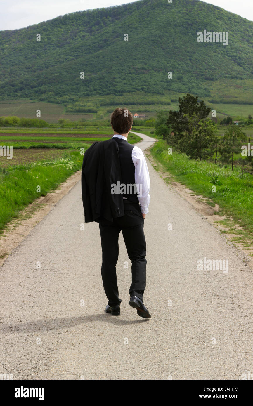 Empresario en el camino, mirando hacia la montaña por delante
