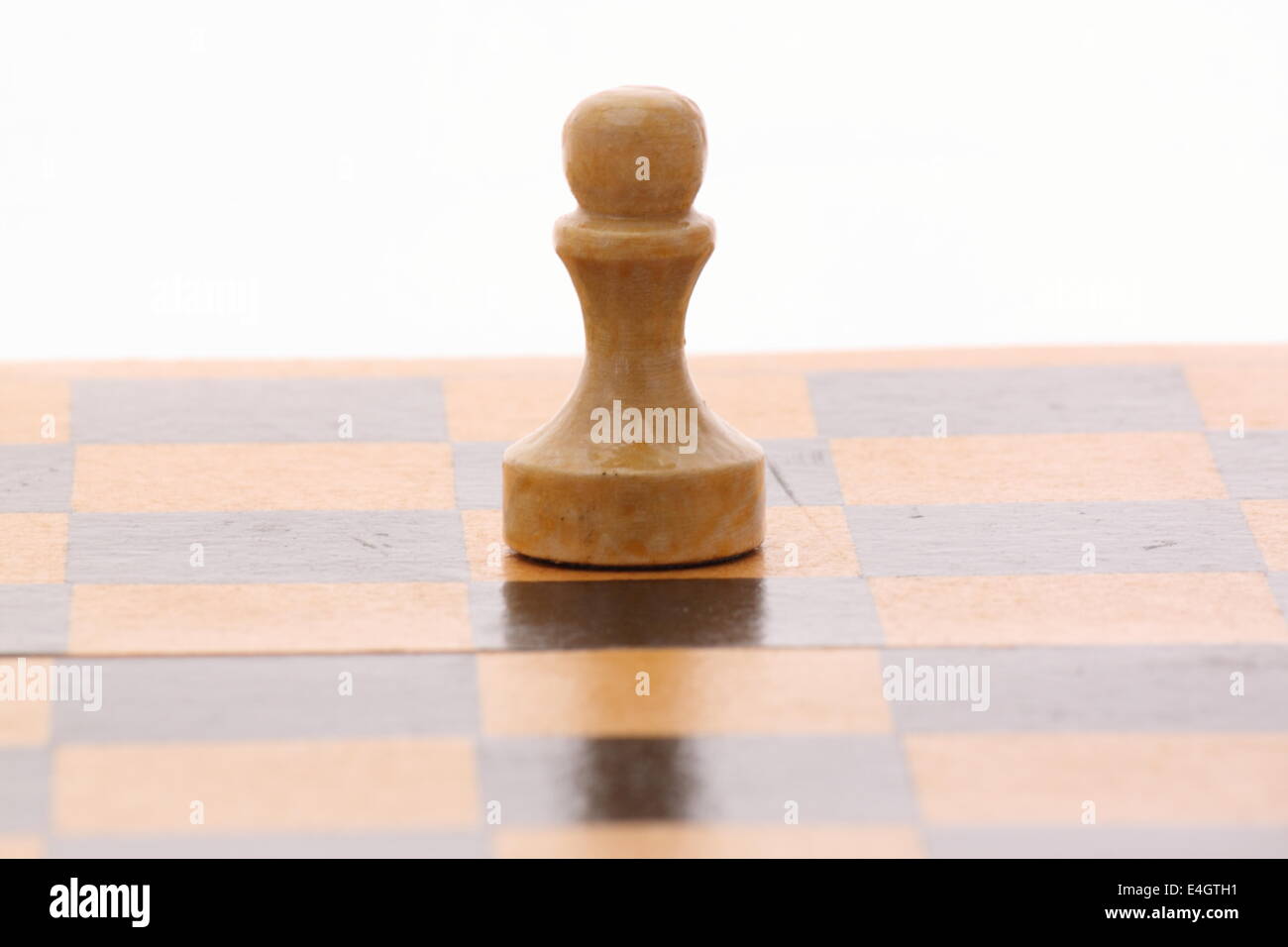 Peón en un tablero de ajedrez de madera sobre blanco Foto de stock