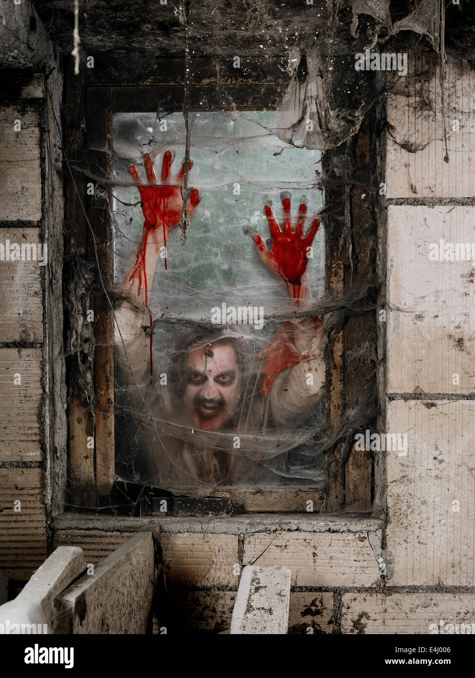 Foto de un zombie hambriento mirando a través de una ventana sucia. Foto de stock