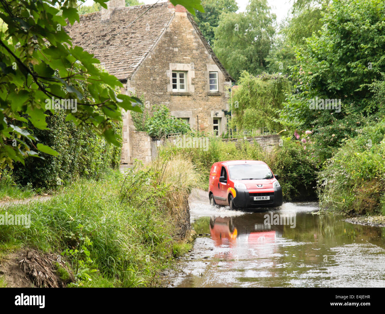 Un pintoresco pueblo Lacock en Wiltshire, Inglaterra Royal Mail delivery impulsa a través de la Ford. Foto de stock