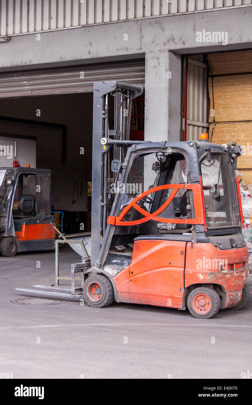 Montacargas pequeño naranja estacionado en un depósito utilizado para