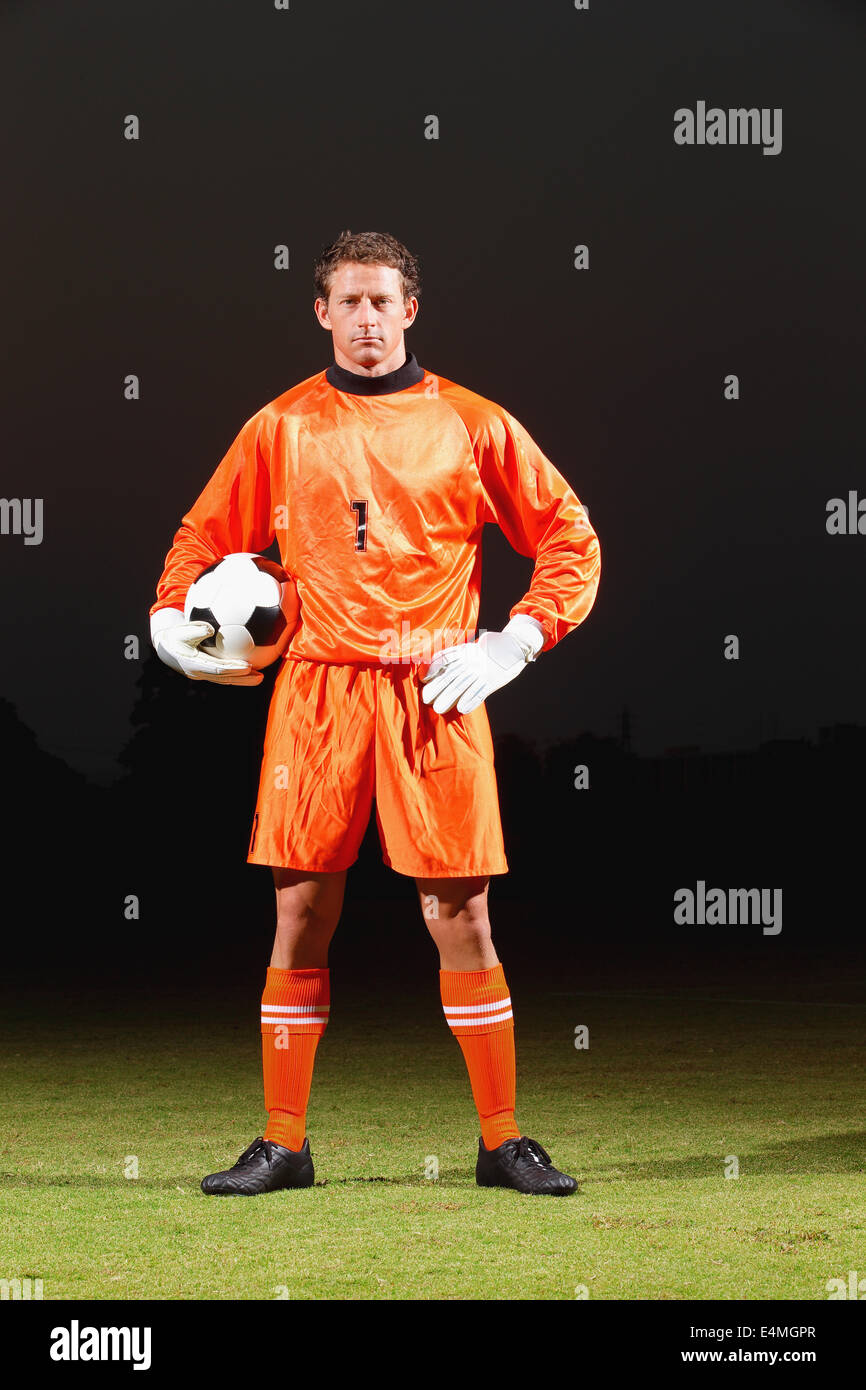 Ajustamiento Supone Depresión Portero en el uniforme naranja de pie en campo de fútbol Fotografía de  stock - Alamy
