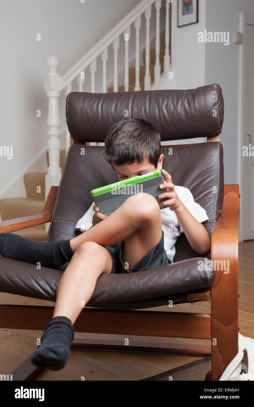 Niño juega en un tablet en casa Foto de stock