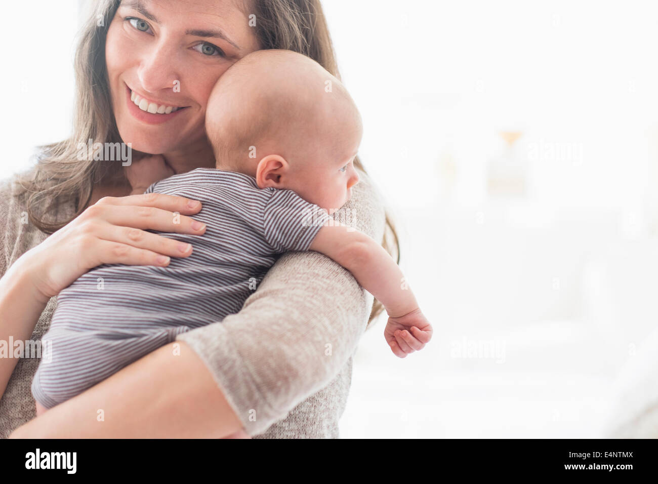 Retrato de madre sonriente Celebración Baby Boy (2-5 meses) en su brazo Foto de stock