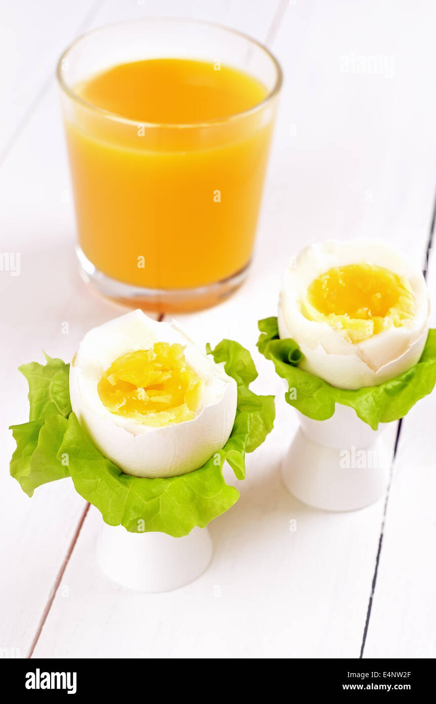 Huevos cocidos en tazas de huevo y zumo de naranja sobre la mesa