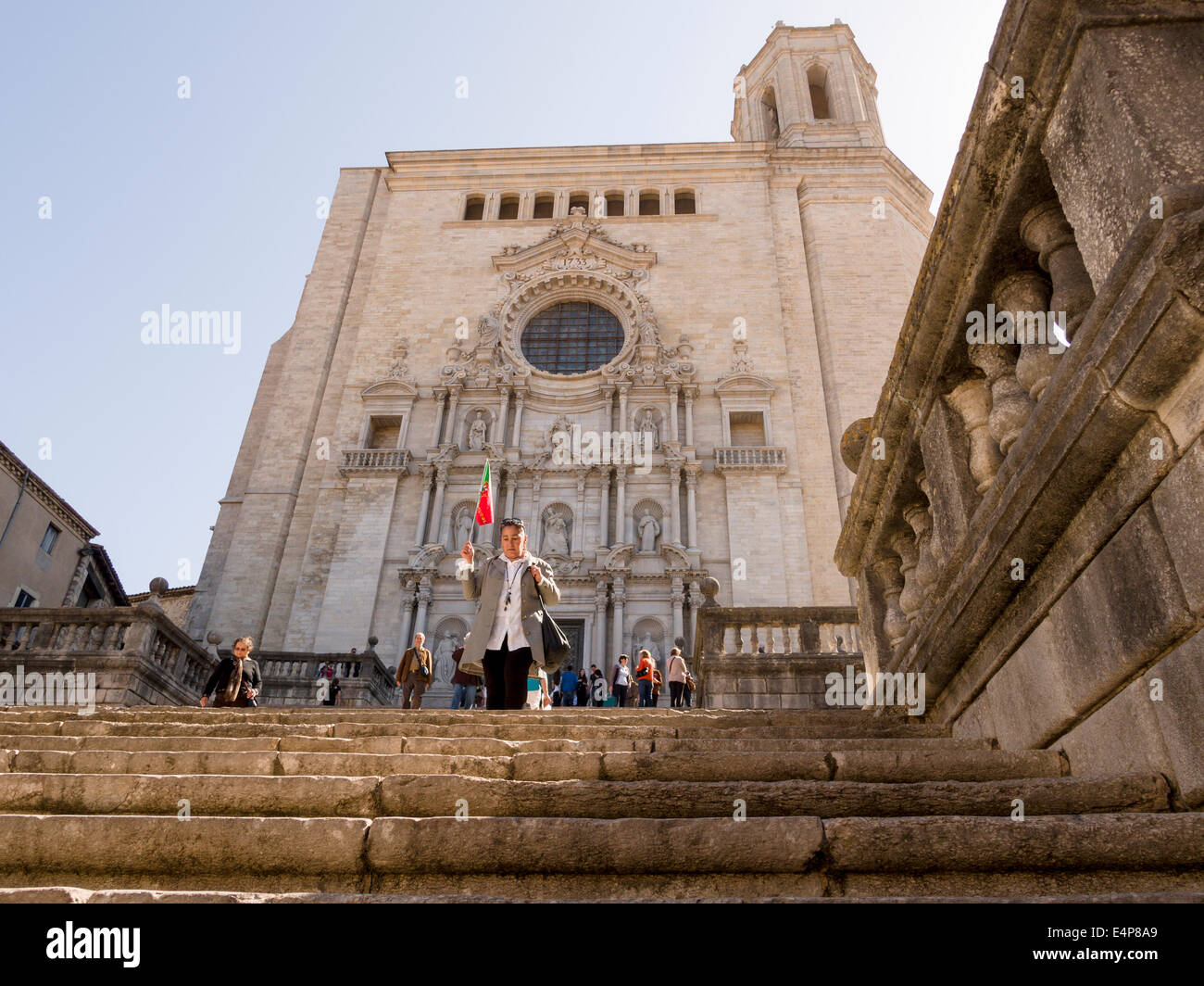Viaje en grupo dejando la catedral de Girona. Un tour líder del grupo agitando una bandera portuguesa lidera un grupo de turistas hacia abajo los pasos Foto de stock