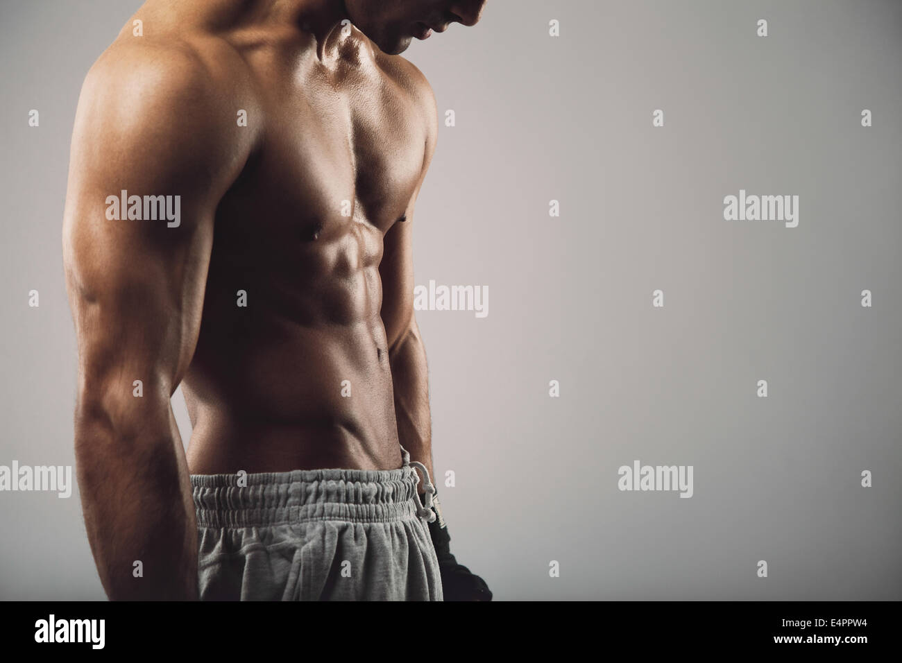 Imagen recortada del masculino joven sobre fondo gris con espacio de copia. Entrenamiento de fitness y tema. Foto de stock