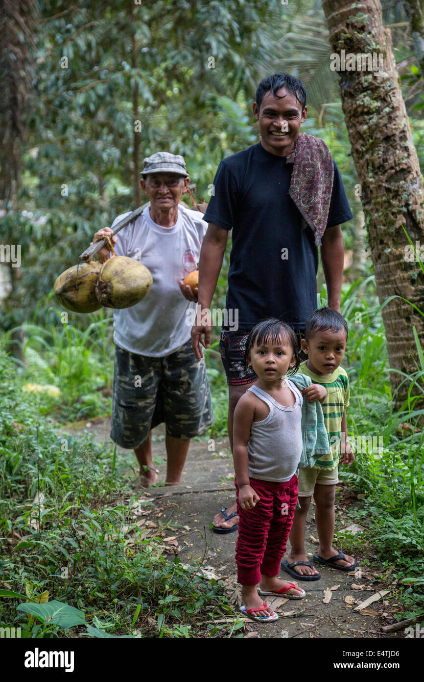 Bali, Indonesia. Los niños balineses hindú con padre y amigo en un camino forestal. Foto de stock