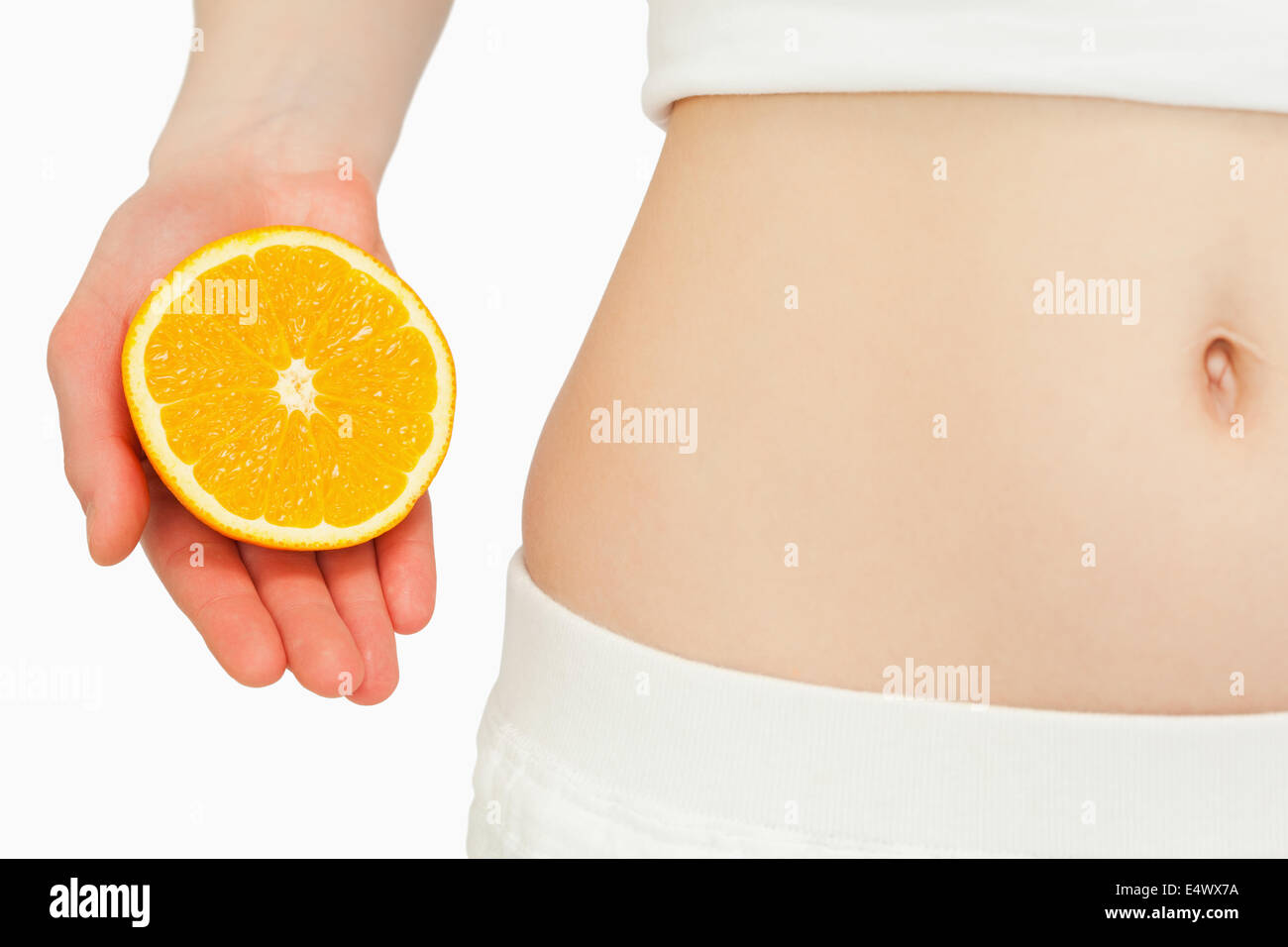 Mujer colocando una naranja cerca de su vientre Foto de stock