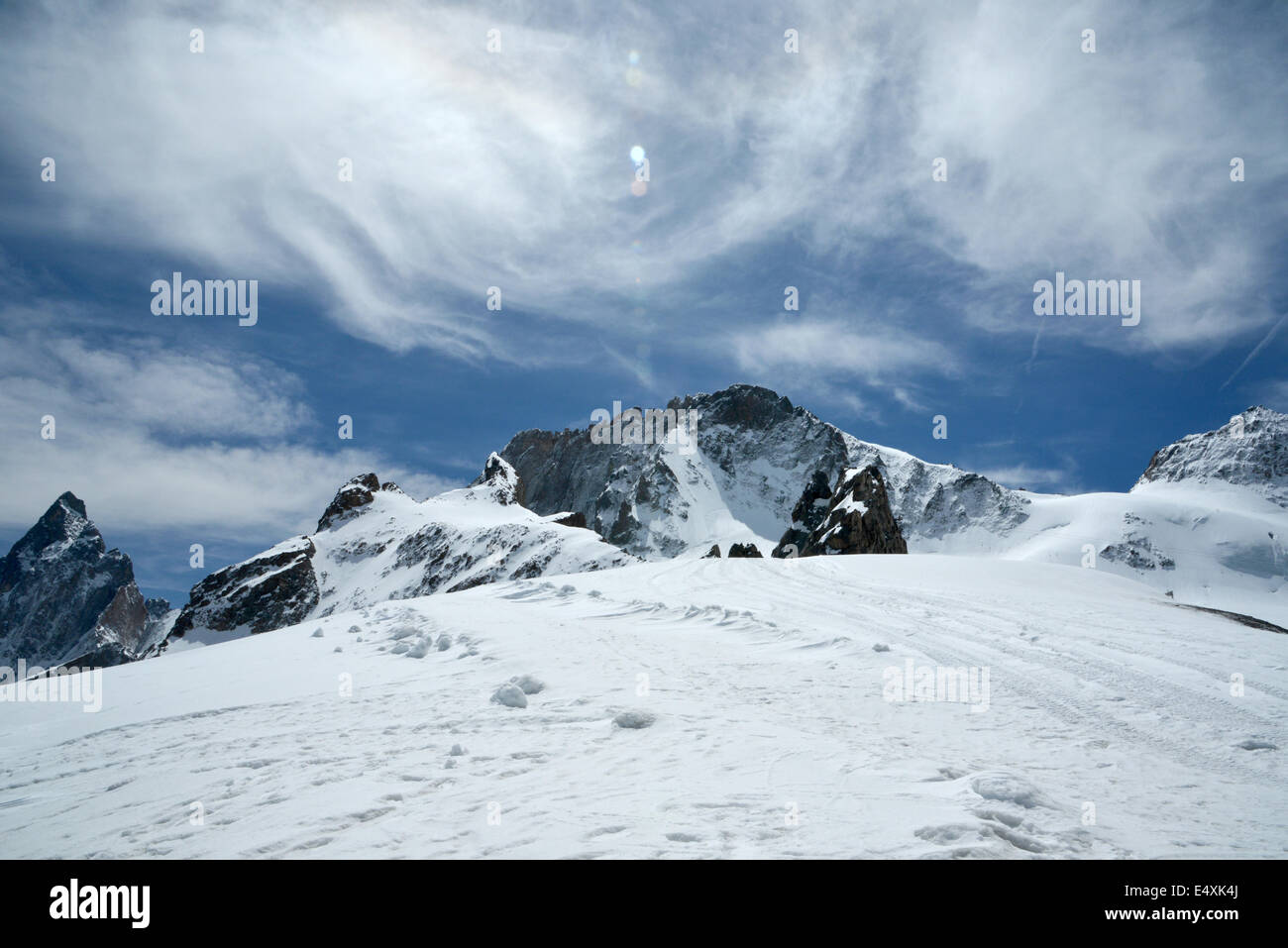 El sol brillante resplandece sobre la nitidez del blanco de la nieve en la cima de una montaña alpina bajo un cielo azul profundo Foto de stock