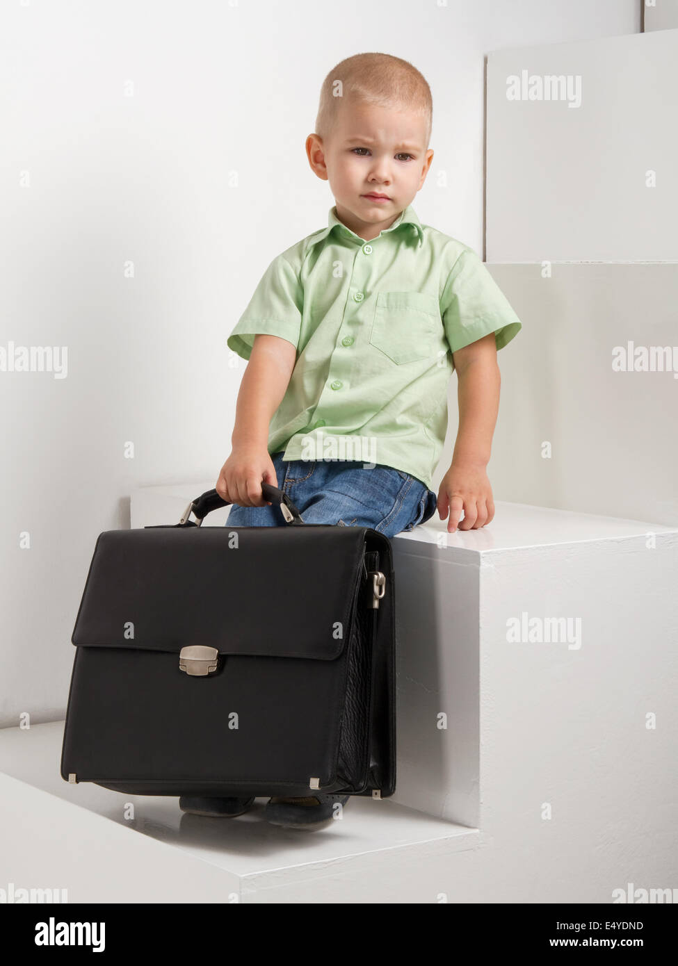 Triste kid con maletín en escaleras de luz de fondo Foto de stock