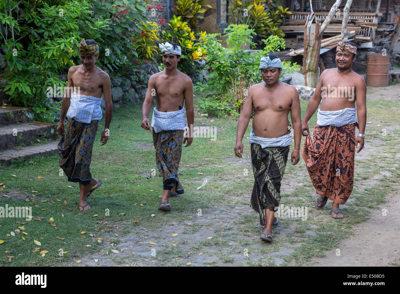 Tenganan, Bali, Indonesia. Los hombres se dirigían a una ceremonia religiosa, vistiendo pareos y udengs tradicional, hombre de cabeza envuelva. Foto de stock
