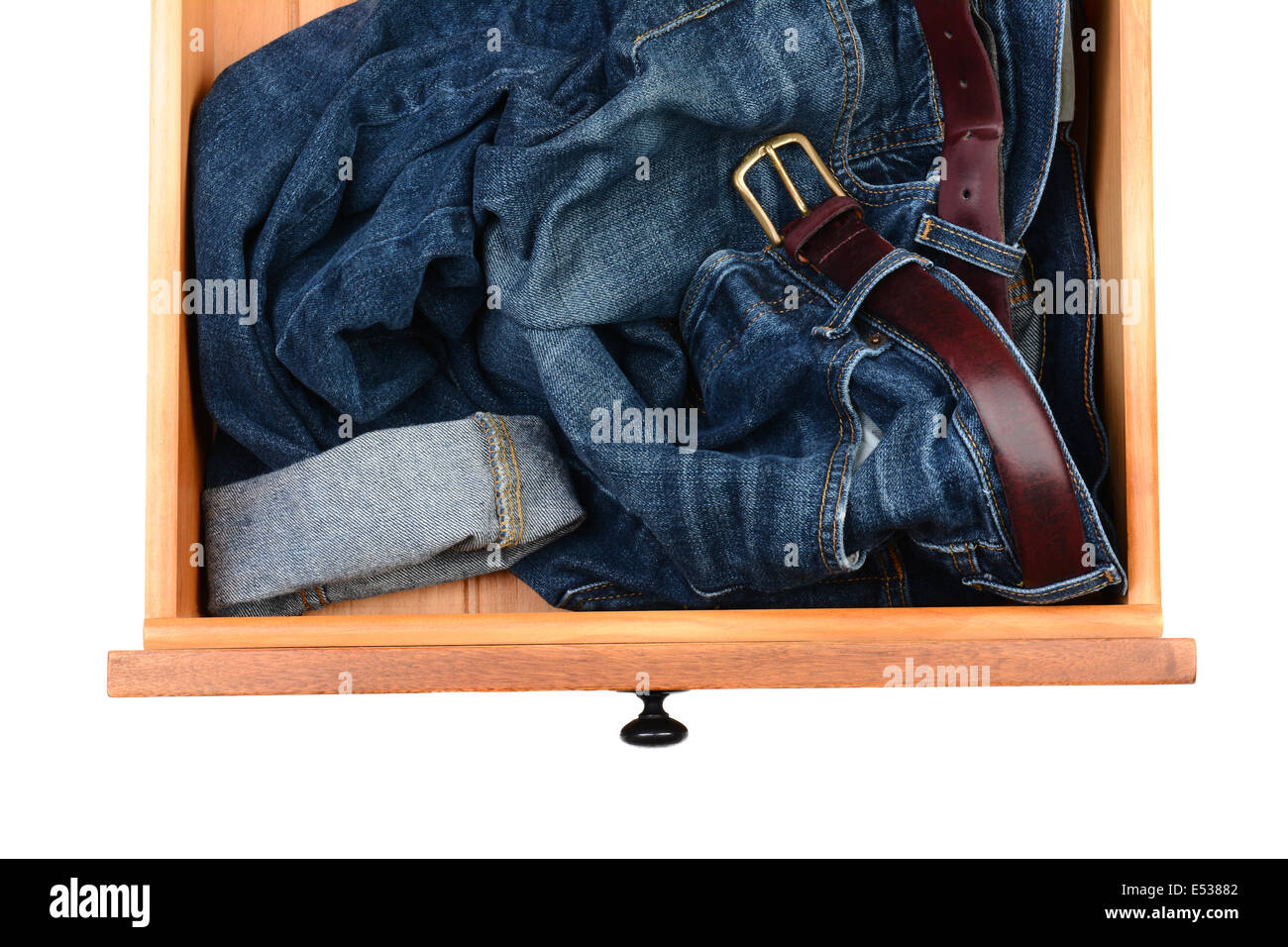 Un alto ángulo de disparo de un par de blue jeans arrugados en un cajón del aparador. Formato horizontal aislado en blanco. Foto de stock