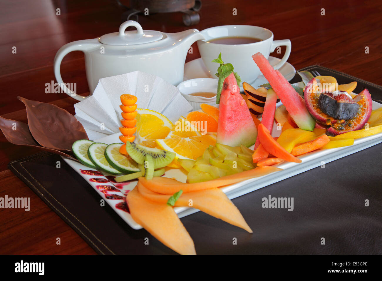 Plato de desayuno de fruta fresca y una olla de té Foto de stock