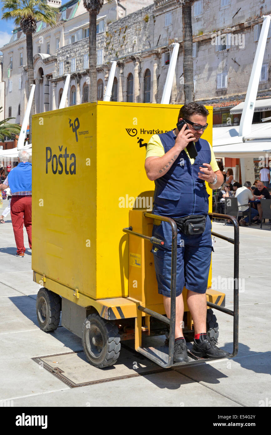 Cartero haciendo una llamada telefónica mientras está parado en un inusual Posta entrega el vehículo en el centro de la ciudad de Split servicio postal Foto de stock