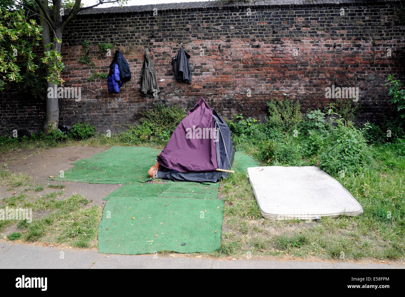 Las personas sin hogar tienda el camino de sirga de Regent's Cannal con abrigos de colgar en la pared detrás y alfombras y colchones alrededor, Londres Foto de stock