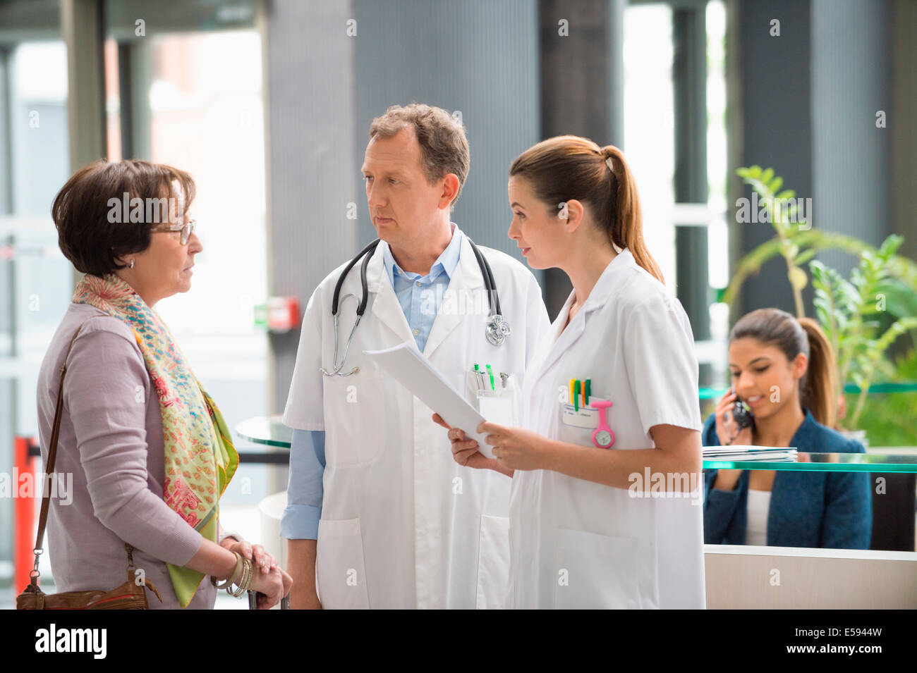 Los médicos discutiendo con el paciente en el hospital de recepción Foto de stock