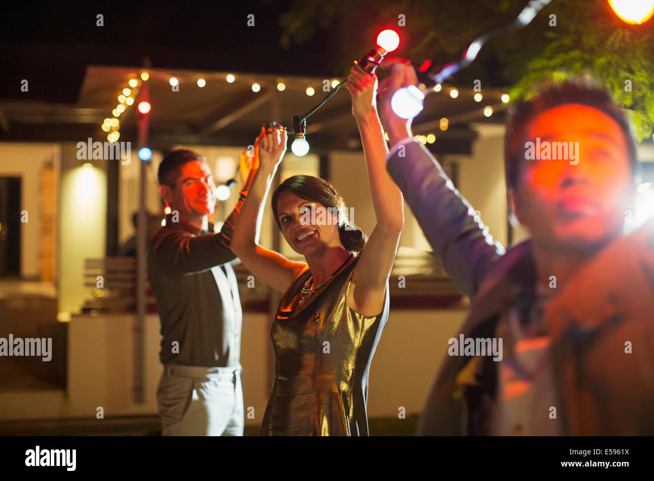 Amigos ensartar luces en la fiesta al aire libre Foto de stock